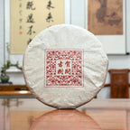 2016 He Kai Raw Pu-erh Tea Cake displayed in a Chinese tea store, showcasing authentic aged Pu-erh tea
