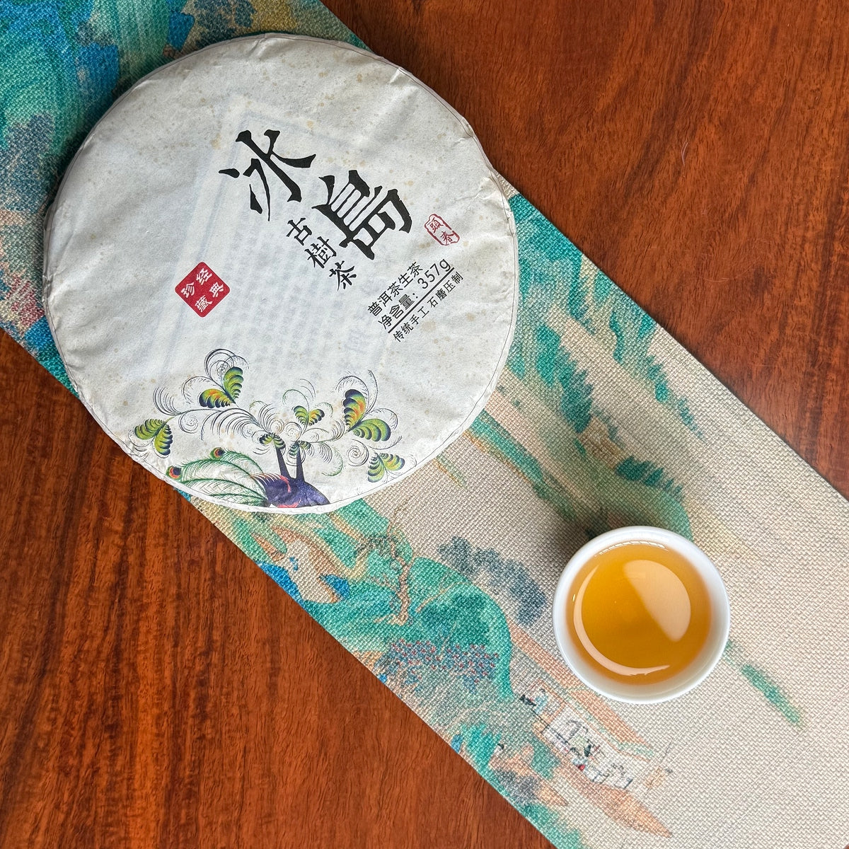 2018 Bing Dao Raw Pu'er Tea Cake Sample with brewed tea beside the whole cake