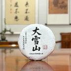 2023 Da Xue Shan Ancient Tree Raw Pu-erh Tea Cake with traditional tea packaging display