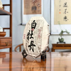 Side view of 2025 Bai Mu Dan White Tea Cake showing the traditional pressed cake shape.